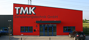 Seitenansicht der Fertigungshalle von TMK, rot gestrichen mit TMK Logo